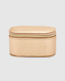 A closed champagne jewellery box with a light gold zipper and a subtle stripe logo on the interior lid.