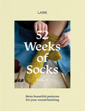 Cover of the book '52 Weeks of Socks Volume II' featuring a close-up of a person's legs wearing yellow socks, with the Laine brand logo and the title of the book.