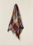Plaid blanket with a geometric pattern draped over a light beige wall.